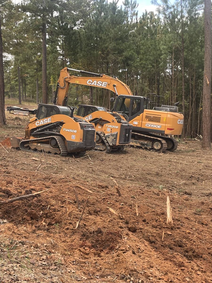 Excavator and two track loaders clearing in the pines